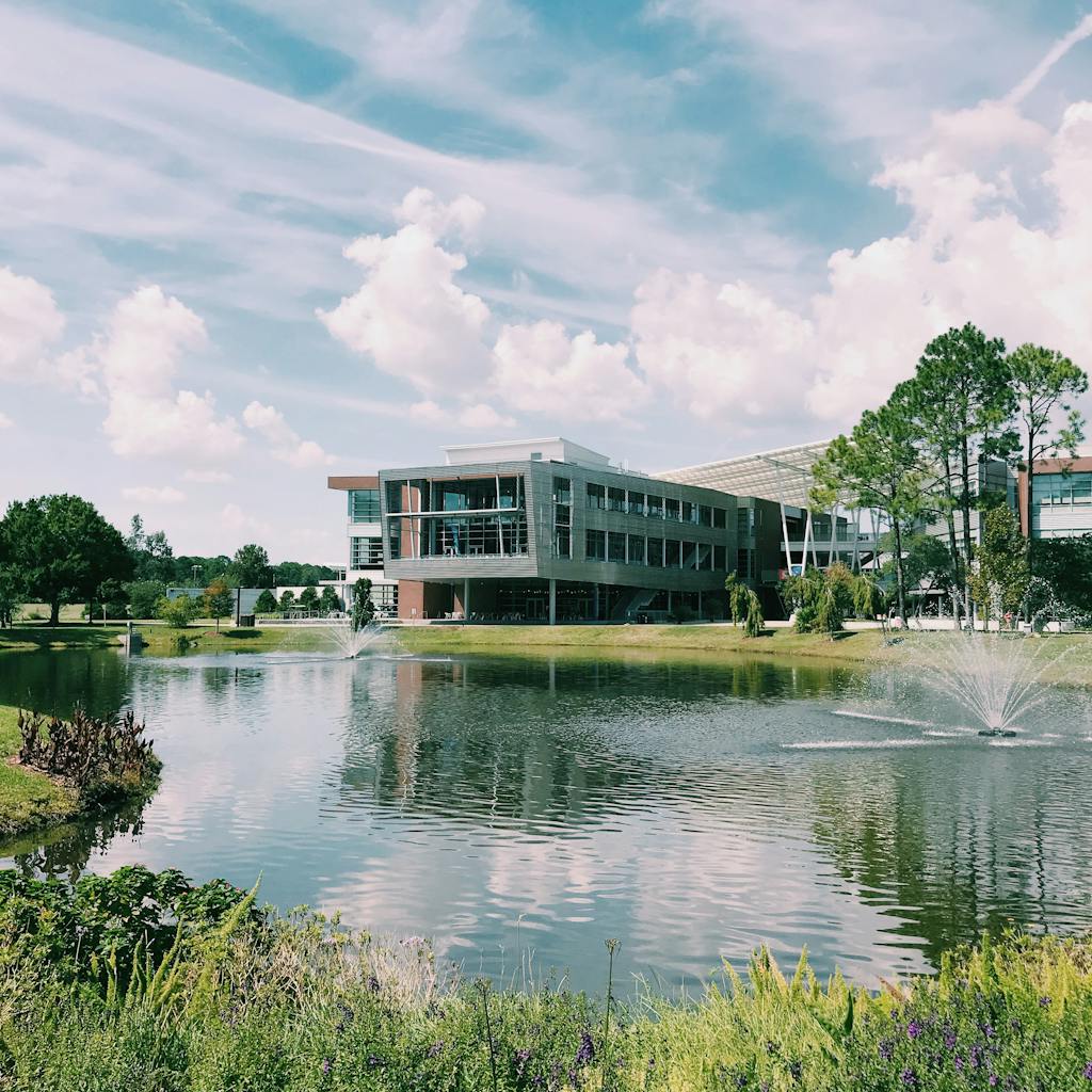 Contemporary building near a pond with a fountain in Jacksonville, FL, on a sunny day.