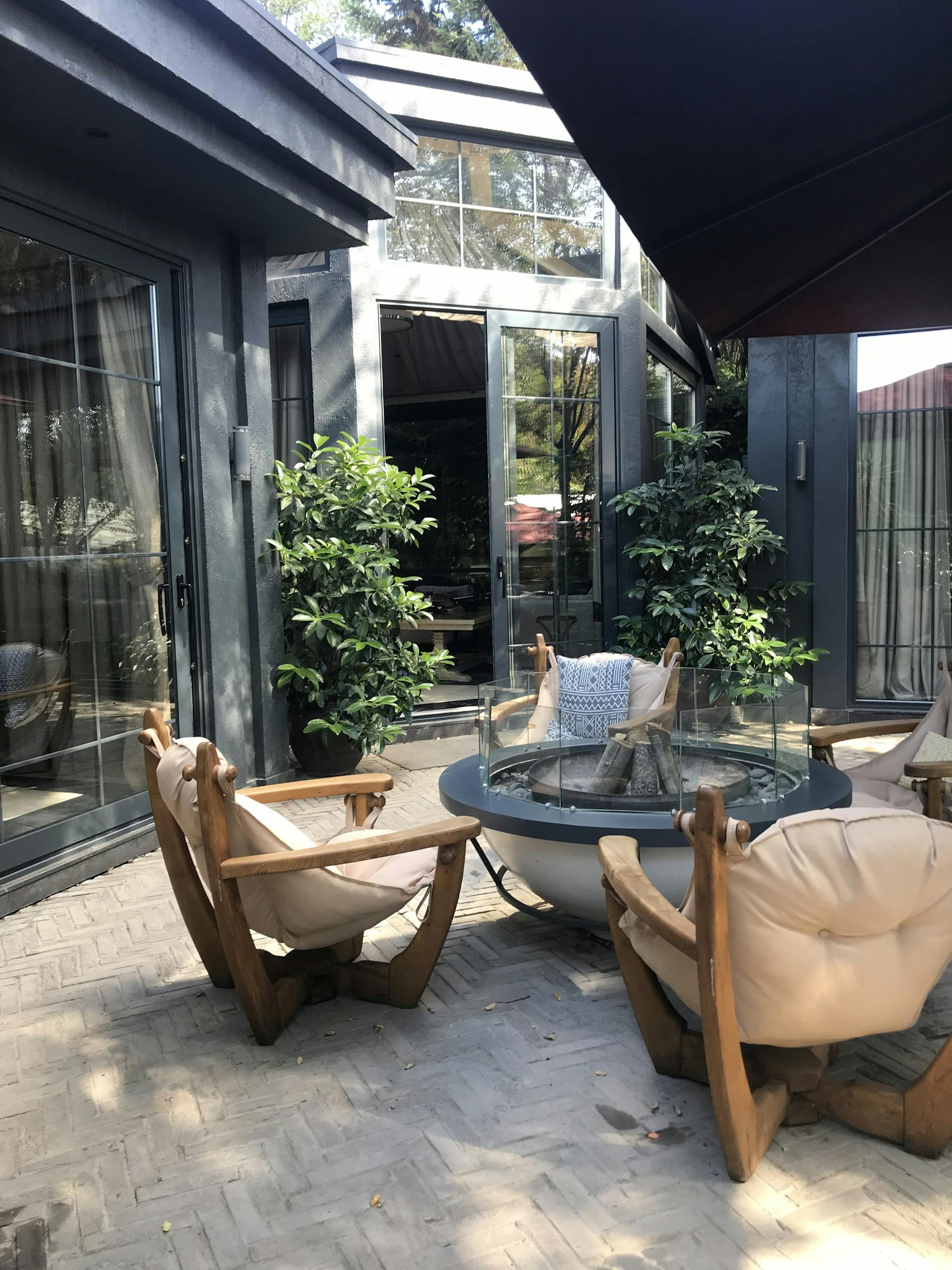 Inviting outdoor patio setting with wooden lounge chairs surrounding a fire pit and lush greenery.